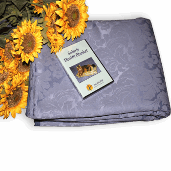 Lavender patterned Solaris Health Blanket with instructional booklet and sunflowers.